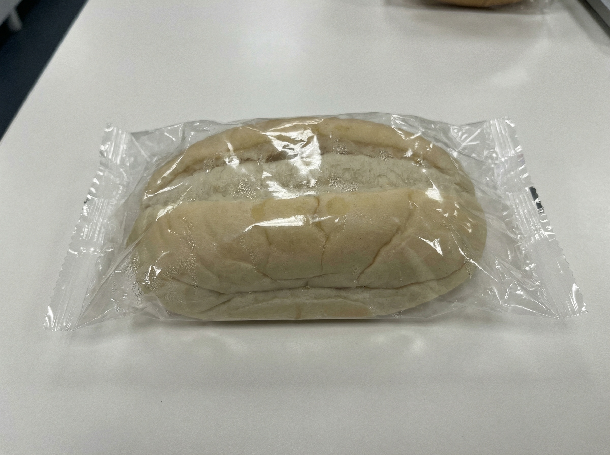 Blasses, eingeschweißtes Supermarkt-Brötchen auf weißem Untergrund